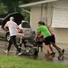 Young Men Push Elderly Woman in Broken Scooter Home in the Pouring Rain